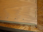 Closeup of the inside of the side panel showing the biscuits, the holes for mounting the shelf, and the rabbet created to hold t